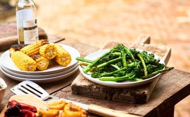 Choclos y espárragos en un asado vegetariano Choclos y espárragos sobre una mesa de madera en un asado vegetariano