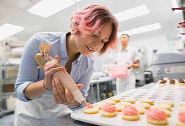 Una mujer usando una manga pastelera, un utensilio de repostería.