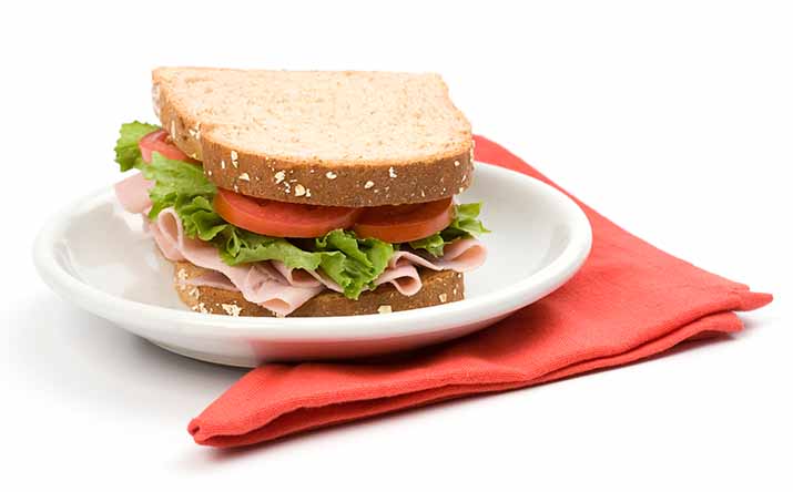 Un sándwich clásico de jamón, lechuga y tomate, uno de los snacks saludables más populares Un sándwich clásico de jamón, lechuga y tomate, uno de los snacks saludables más populares