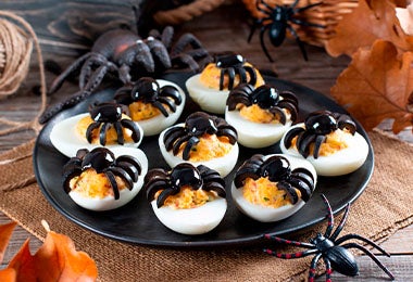 Huevos arácnidos sobre un plato negro para una fiesta de Halloween. Huevos arácnidos sobre un plato negro para una fiesta de Halloween.