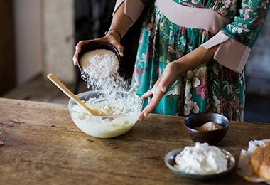 Mujer añadiendo harina a su mezcla de crema pastelera. Mujer añadiendo harina a su mezcla de crema pastelera.