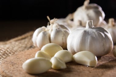 Ajos y cascos de ajo sobre una tabla de picar para la langosta al ajillo.