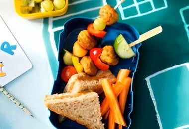 Lonchera para alimentación escolar con sándwich integral, brochetas de pollo y frutas