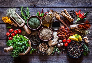 Vista superior de ingredientes como especias, tomates cherry y jengibre. Destacan algunos condimentos que incluyen alimento de origen mineral