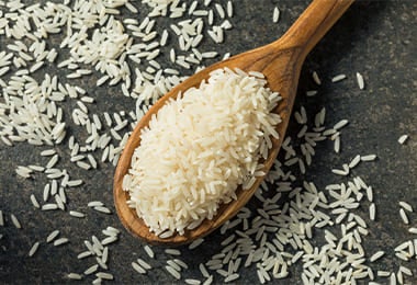 Cucharada de madera llena de arroz crudo para hacer rollos de sushi vegano.