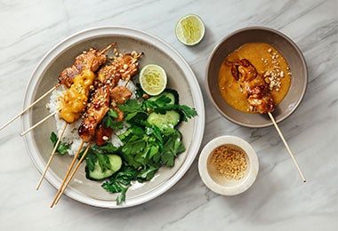 Brochetas de pollo con salsas coreanas, arroz blanco, pepino en rodajas y perejil fresco