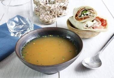 Plato hondo con caldo de hueso de pollo acompañado de wraps
