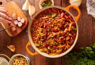 Cassoulet servido en olla con porotos, salchichas y vegetales frescos