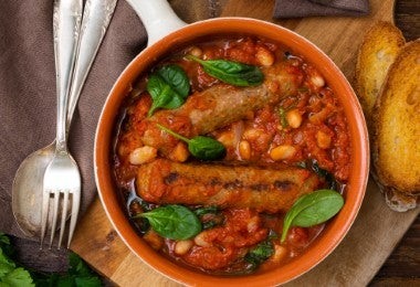 Cassoulet con salchichas, porotos y salsa de tomate servido en sartén