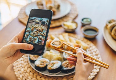Una persona celebrando el Día Internacional del Sushi tomando una foto desde su celular.
