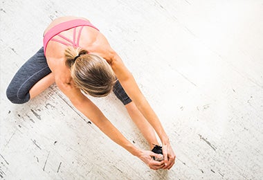 Una mujer estirando su cuerpo antes de hacer ejercicio en casa en su rutina de vida activa