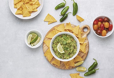 Nachos acompañados de guacamole, ají casero, chiles y limón