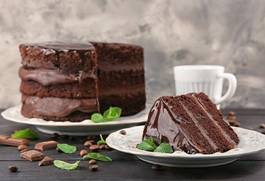 Un naked cake de chocolate y frutos secos, con una rebanada cortada y servida en un plato. 