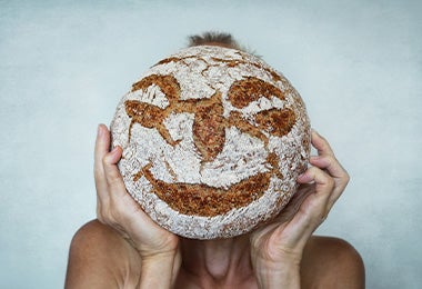 Cobertura de pan de masa madre con granos de centeno en unas manos