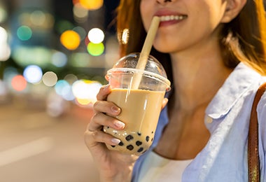 Mujer tomando un té con perlas de tapioca hechas a través de la esferificación.
