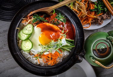 Plato servido en olla de piedra con vegetales, carne, huevo y un toque de ají cacho de cabra