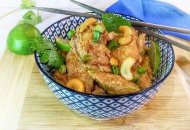 Bowl con pollo en salsa de castañas de cajú, decorado con cebolla fresca, cilantro y acompañado de limón y palillos