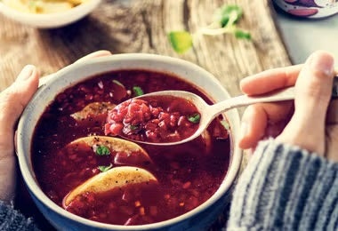 Persona consumiendo sopa caliente con bulgur y betarraga