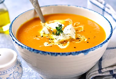 Crema de zapallo italiano y almendras en un plato hondo blanco.