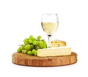 Tabla de quesos con uvas verdes y vino blanco para acompañar las aceitunas rellenas.