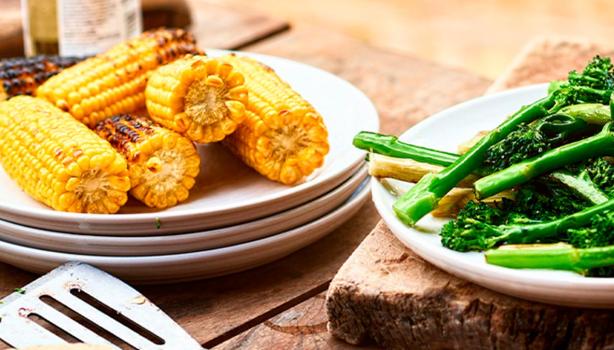 Choclos y espárragos sobre una mesa de madera en un asado vegetariano