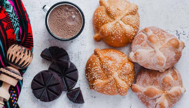 Panes dulces mexicanos tradicionales acompañados de chocolate caliente y un molinillo