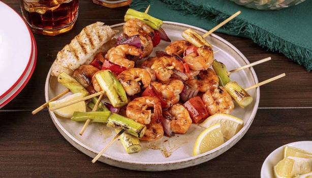 Pinchos con camarones y langostinos al ajillo con verduras y rodajas de limón mandarino