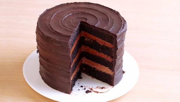 Una Tarta Sacher redonda con su interior descubierto sobre un plato blanco.  