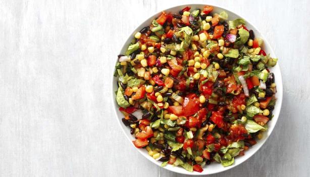 Una ensalada cremosa con maíz, tomate y palta en toma cenital.