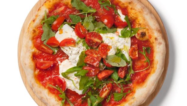 Focaccia italiana con pasta de tomate, queso burrata y rúgula encima, vista desde un plano cenital.
