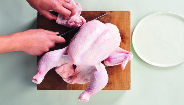 Corte de la carcasa de pollo sobre una tabla de madera, ideal para usar en caldos de hueso de pollo