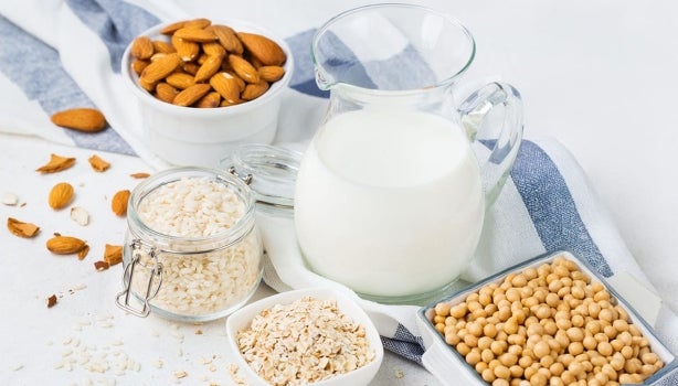 Jarra de vidrio de crema vegetal de almendras, junto a snacks de frutos secos.
