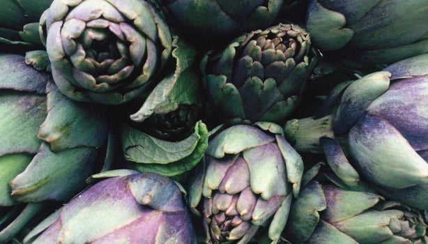 Alcachofas frescas verdes y moradas en primer plano, perfectas para conocer mejor para qué sirve la alcachofa en recetas