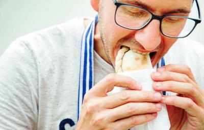 Un hombre comiendo una empanada tucumeña, una clase de empanada argentina. Un hombre comiendo una empanada tucumeña, una clase de empanada argentina.