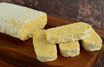 El tempeh es una carne vegetal de origen indonesio. Tempeh, una carne vegetal, sobre una mesa de madera.