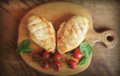 Dos pechugas de pollo con un racimo de tomates cherry, una comida con proteínas magras encima de una tabla