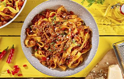 Pasta a la boloñesa con carne, queso parmesano y hierbas aromáticas sobre un fondo amarillo Pasta a la boloñesa con carne, queso parmesano y hierbas aromáticas sobre un fondo amarillo