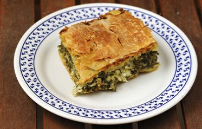 Una porción de la receta griega spanakopita sobre un plato blanco y azul. Una porción de la receta griega spanakopita sobre un plato blanco y azul.