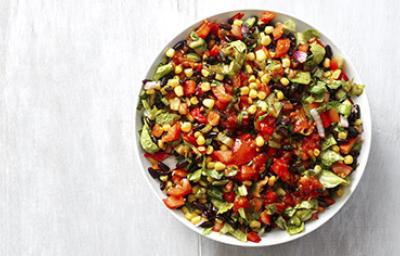 Una ensalada cremosa con maíz, tomate y palta en toma cenital.