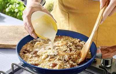 Una persona preparando una receta de cocción lenta con champiñones, crema y arroz