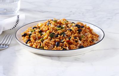 Toma lejana de arroz negro con cubiertos y un vaso de agua