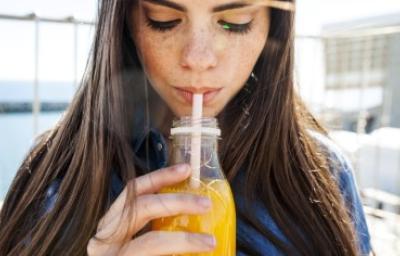 Mujer bebiendo un refrescante jugo de zanahoria con limón.