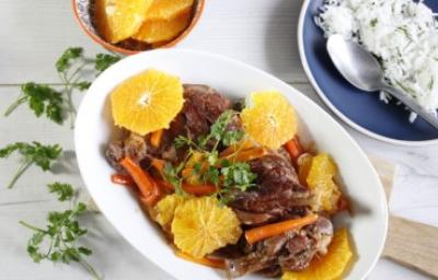 Plato de cerdo con salsa de naranja, acompañado de rodajas de naranja