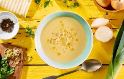 Vichyssoise en un tazón, mesa amarilla con ingredientes frescos