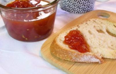 Rebanada de pan con mermelada casera de frutilla, recipiente de vidrio sobre tabla