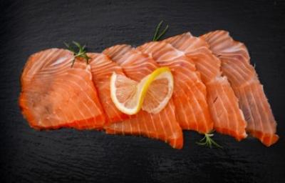 Pequeños trozos de salmón ahumado frío sobre fondo negro.