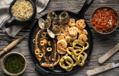 Sartén de hierro fundido con pulpo a la parrilla y variedad de mariscos