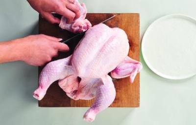 Cómo cortar la carcasa de pollo para preparar caldos y sopas Corte de la carcasa de pollo sobre una tabla de madera, ideal para usar en caldos de hueso de pollo