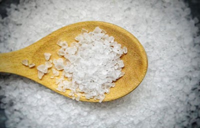 Cuchara de madera con sal marina gruesa, un alimento de origen mineral, sobre una superficie