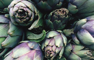 Alcachofas frescas verdes y moradas en primer plano, perfectas para conocer mejor para qué sirve la alcachofa en recetas